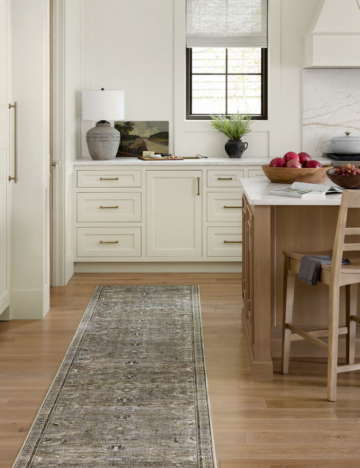 #color::antique-and-moss #size::2-6--x-7-6- #size::2-6--x-9-6- #size::2-6--x-12- | Amalia distressed traditional rug in its runner size lays in a kitchen with white cabinetry and marble countertops