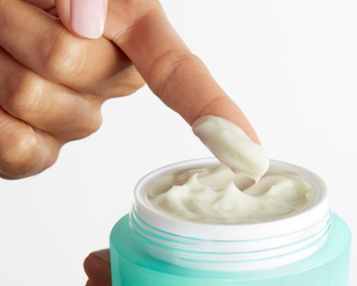 A finger scooping Skinfix Antioxidant Tetrapeptide Soothing Treatment from an open mint green jar.
