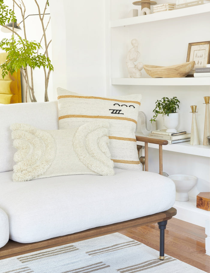 #color::natural #size::lumbar | The arches ivory lumbar pillow sits with another decorative throw pillow atop a white linen sofa with a wooden frame