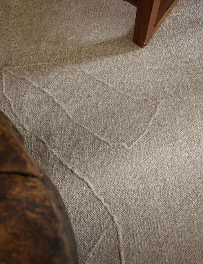 #size::2-6--x-8- #size::6--x-9- #size::8--x-10- #size::9--x-12- #size::10--x-14- #size::12--x-15- | Close up of the beachwood rug under a wooden coffee table and wooden framed accent chair