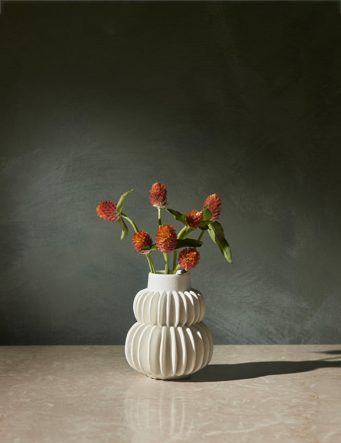#color::white | Delilah white ceramic vase featuring two rows of half-moon discs fanned around a tapered body with flowers inside of it
