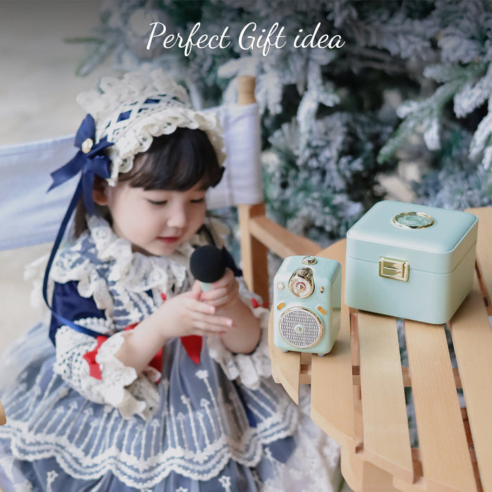 Divoom Fairy-OK Retro Mini Karaoke Speaker, a mint retro mini speaker, matching case and mic beside a child by a Christmas tree, karaoke audio for holiday gift decor