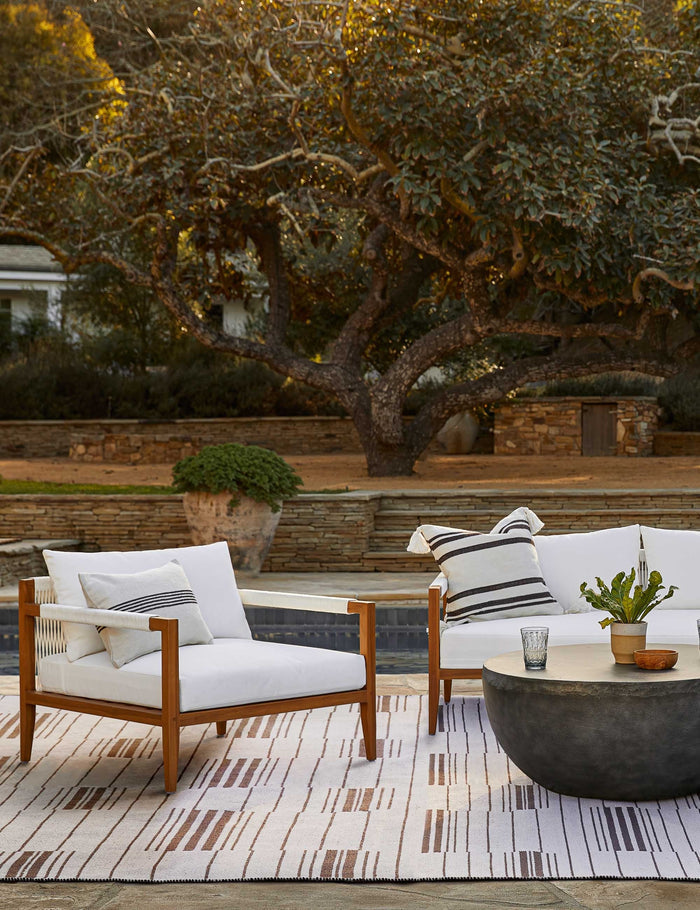 #color::black | The Fez black and white indoor and outdoor throw pillow sits on a white sofa in an outdoor space atop a rug