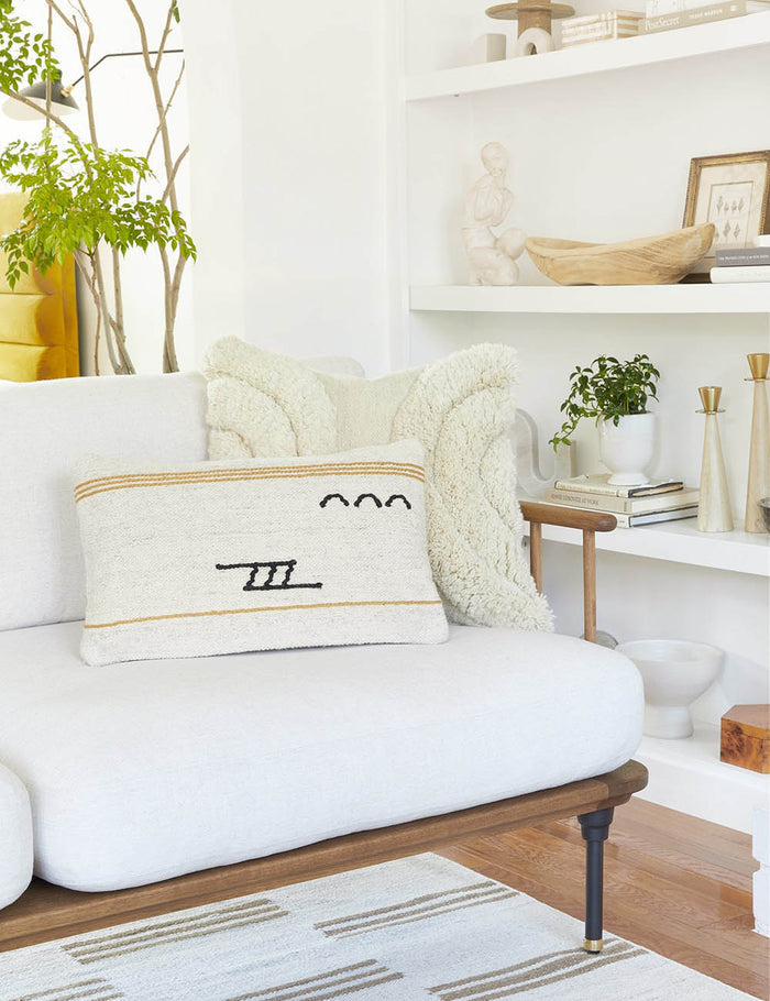 #style::lumbar | The Iconic ivory stripe lumbar pillow sits on a white sofa with a wood frame with a plush ivory square pillow
