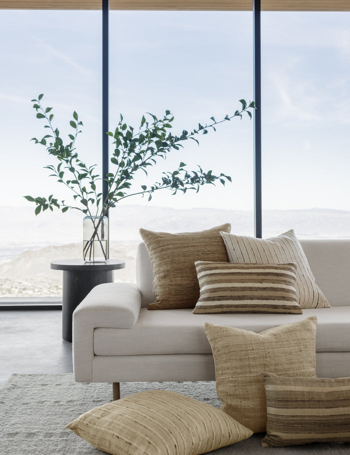 #size::square | The leni square silk pillow sits with other silk pillows in a bright room on a white linen sofa