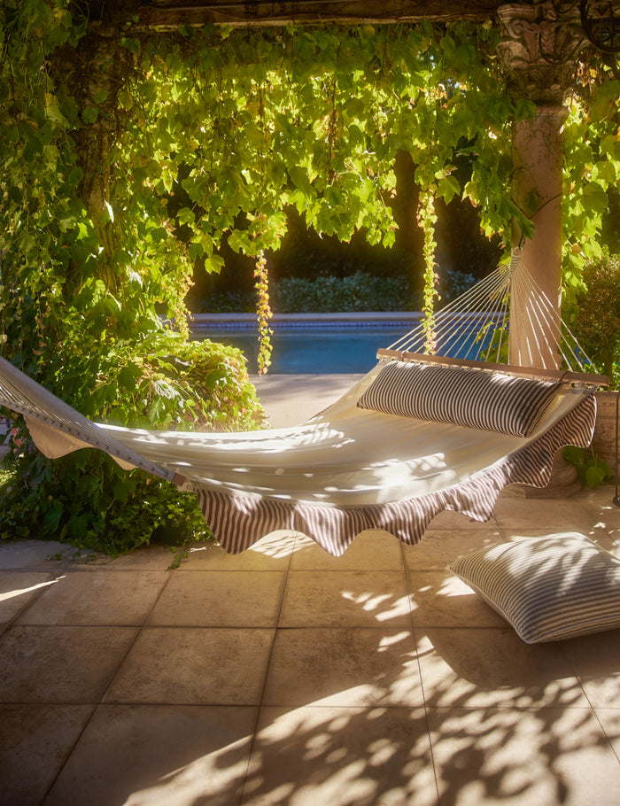 | Levata Striped Hammock by Sarah Sherman Samuel hanging in a covered outdoor space.
