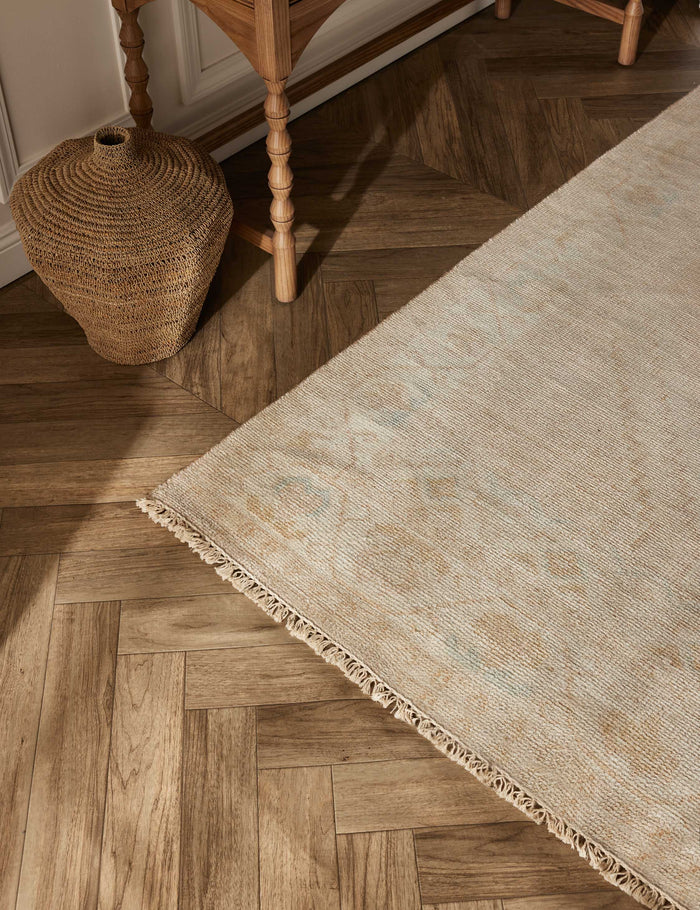#size::2--x-3- #size::4--x-6- #size::6--x-9- #size::8--x-10- #size::9--x-12- #size::10--x-14- | The lotus rug lays on a chevron wooden floor next to a jute basket and a sideboard with sculptural legs
