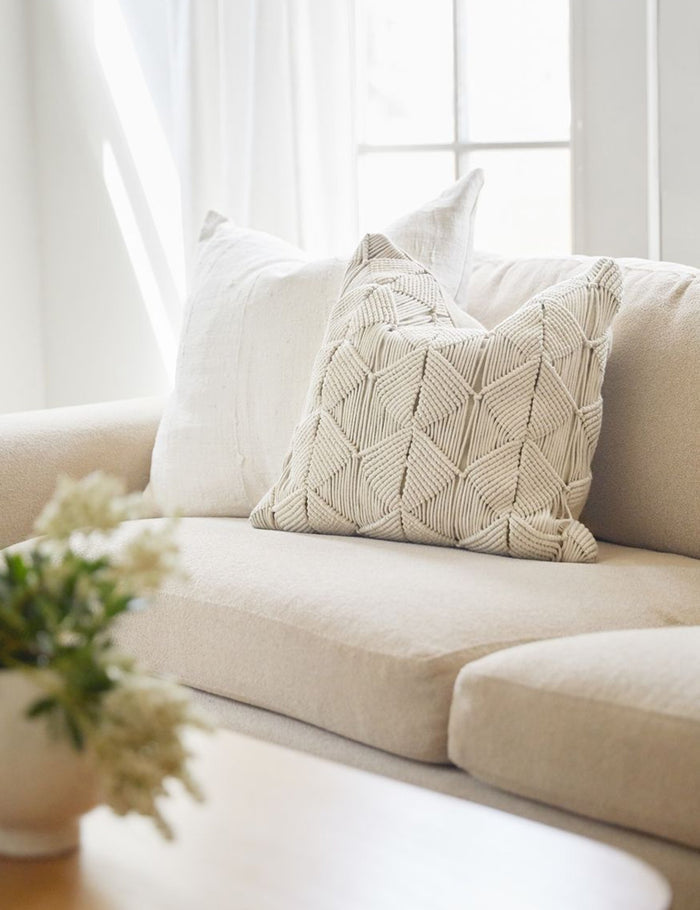#size::20--x-20- | The Norala solid white handmade square throw pillow sits on a natural linen sofa with a white throw pillow behind it