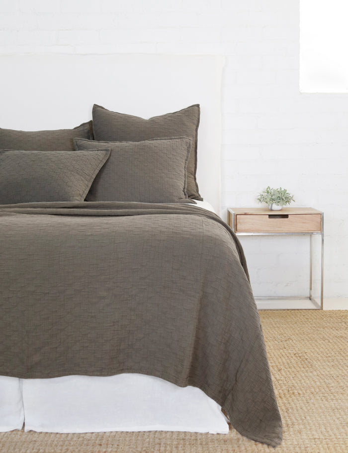#color::pebble #size::euro | Ojai Cotton Matelasse Pebble Gray Euro Sham by Pom Pom at Home sits on a white framed bed with other Ojaj pebble gray linens