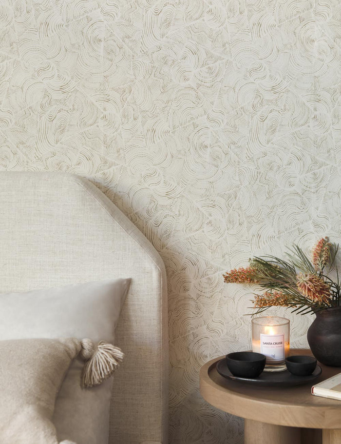| The parma wallpaper is in a bedroom with a natural linen framed bed and a wooden round nightstand