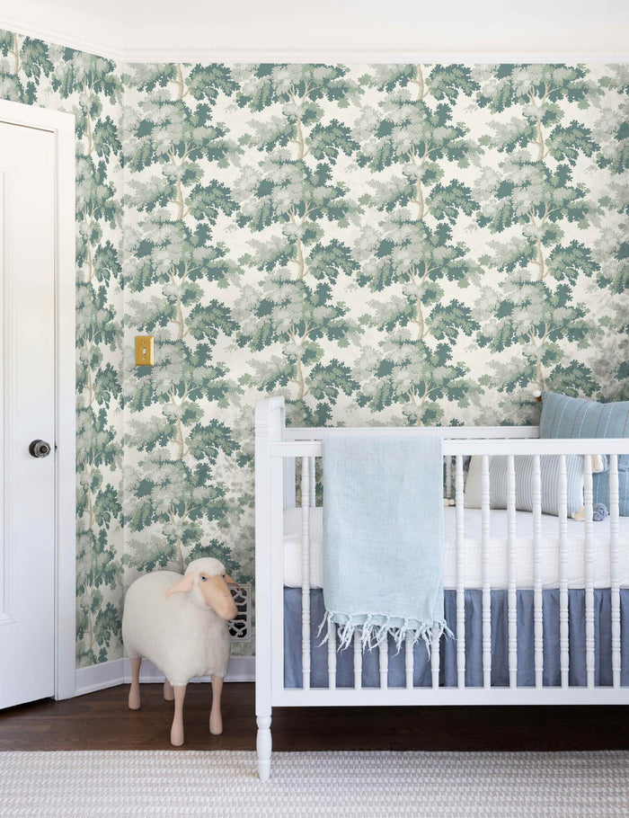 #color::green | The Scalamandre botanical inspired green raphael wallpaper is in a nursery with a white crib and a toy lamb