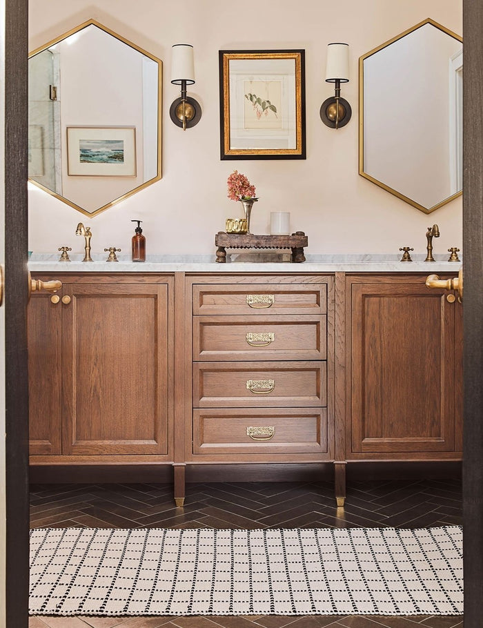 #size::1-9--x-2-10- #size::2--x-5- | The Sebou natural and black dotted machine washable mat in its runner size lays in a bathroom with hexagonal golden framed mirrors