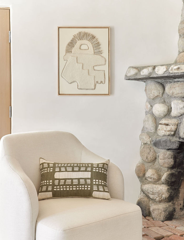 #size::12--x-20- | The Stonewalk green geometric lumbar throw pillow by Élan Byrd sits on a natural linen accent chair to the left of a stone fireplace