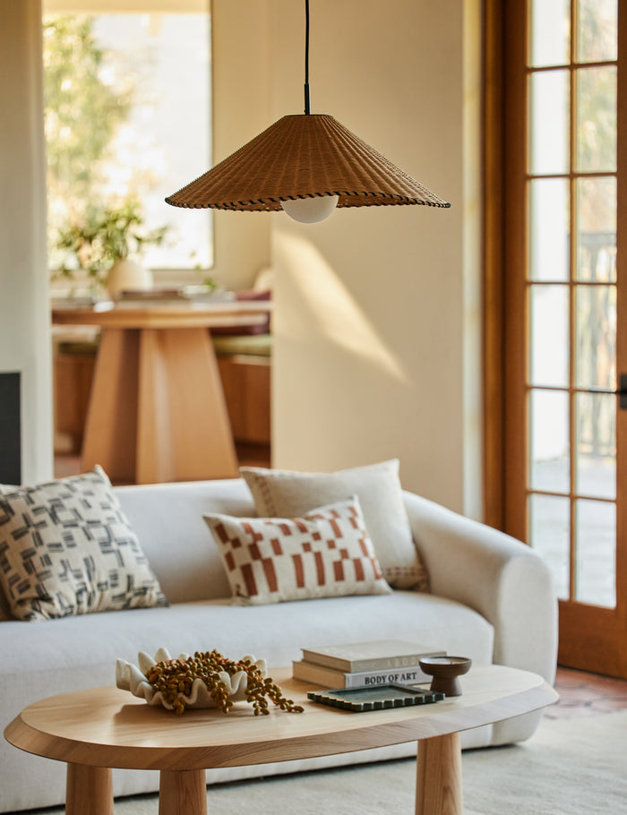 #color::natural #size::25-dia | Terrene Woven Rattan Pendant by Elan Byrd hanging above a coffee table.