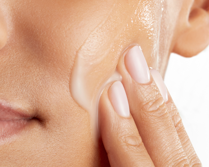 A person applying Skinfix Triple Lipid-Hyaluronate Serum to their cheek and jawline.